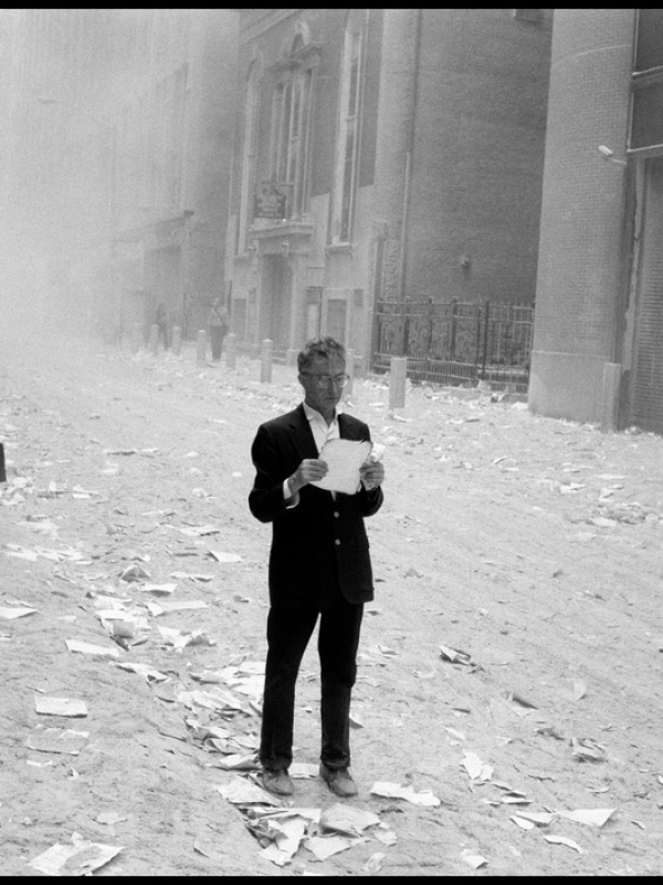 USA. NYC. 9/11/2001. A dazed man picks up a paper that was blown out of the towers after the attack of the World Trade Center, and begins to read it..